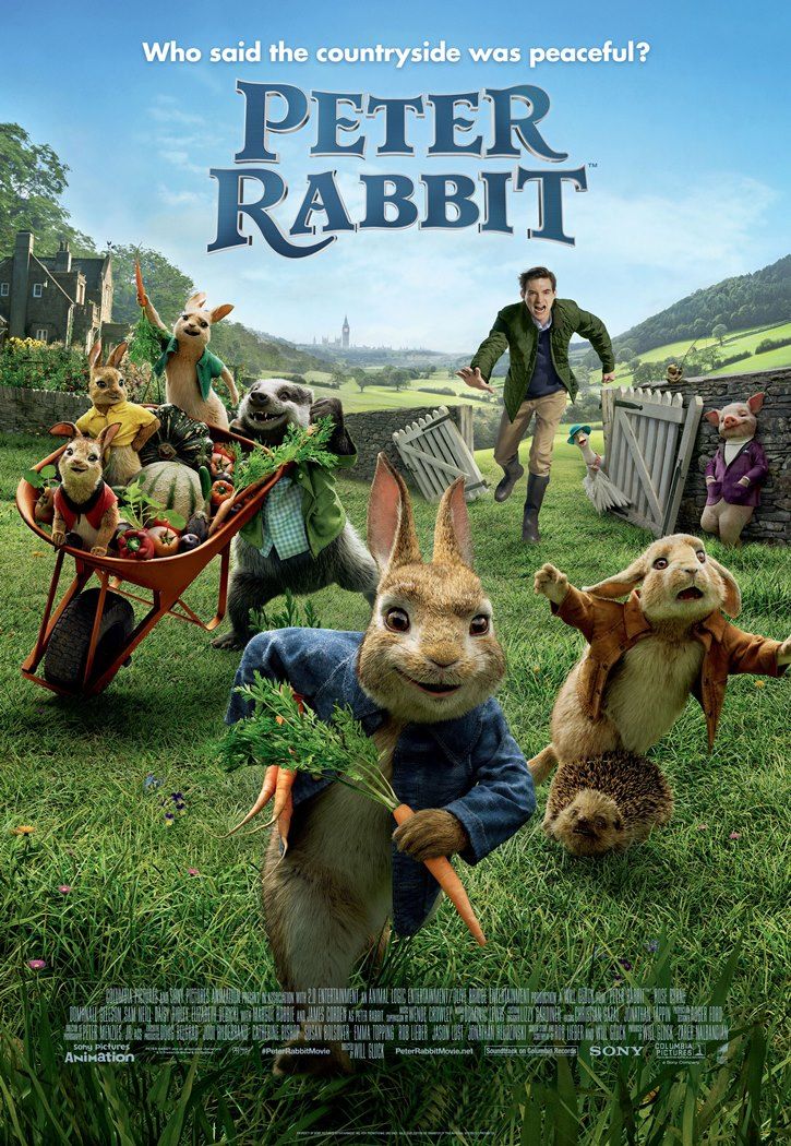 peter rabbit movie poster with rabbits in the grass and people standing around them holding carrots