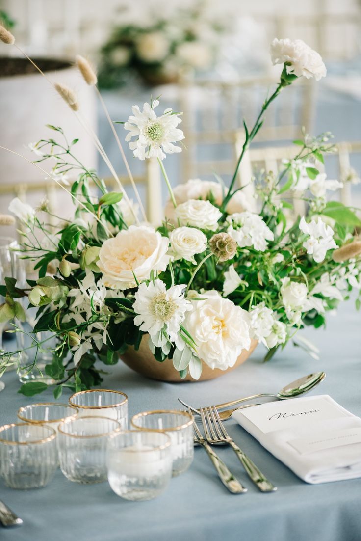 the table is set with white flowers and silverware