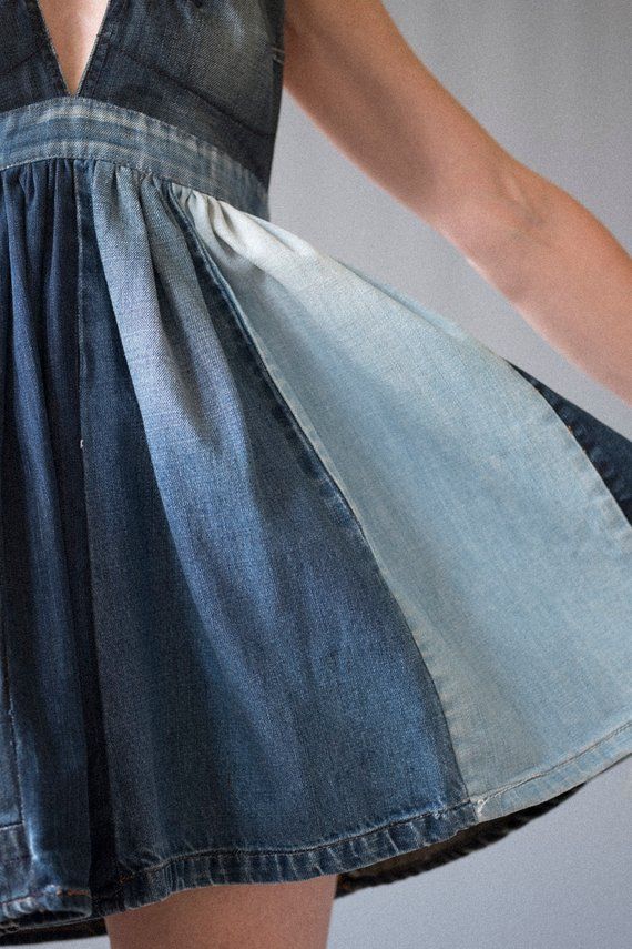 a woman is wearing a dress made out of denim and has her hands on the hips