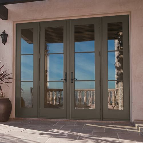 the front door to a home with double doors and large potted plant on the side