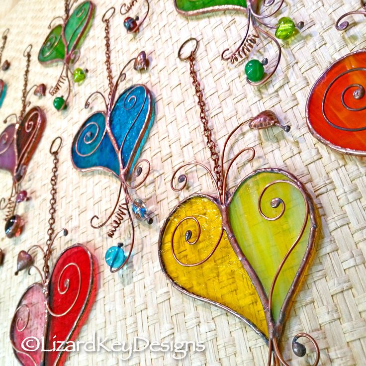 many colorful hearts hanging on a wall with metal chains and glass bead necklaces