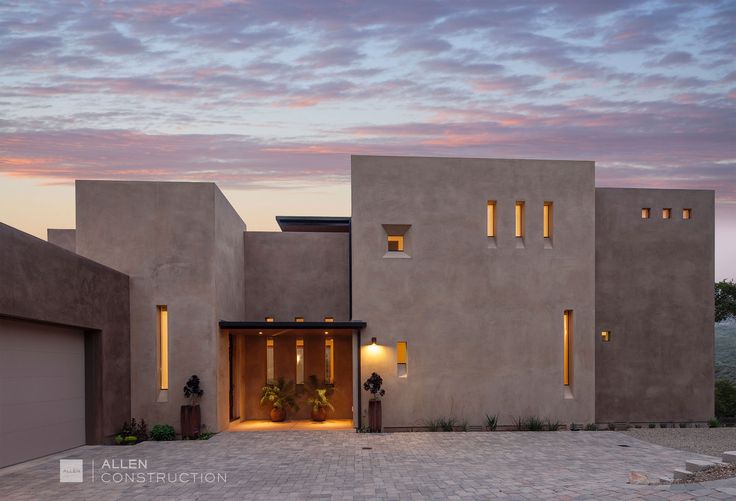 an exterior view of a modern house at dusk with lights on the windows and doors