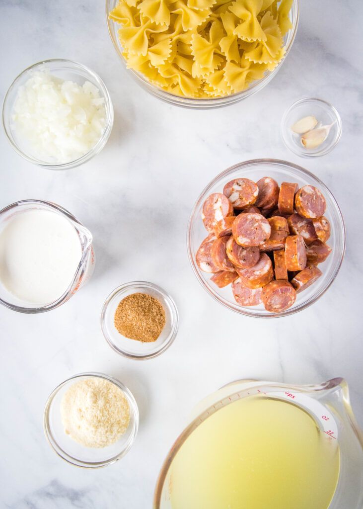 the ingredients to make this dish include pasta, cheese and sausages in small bowls