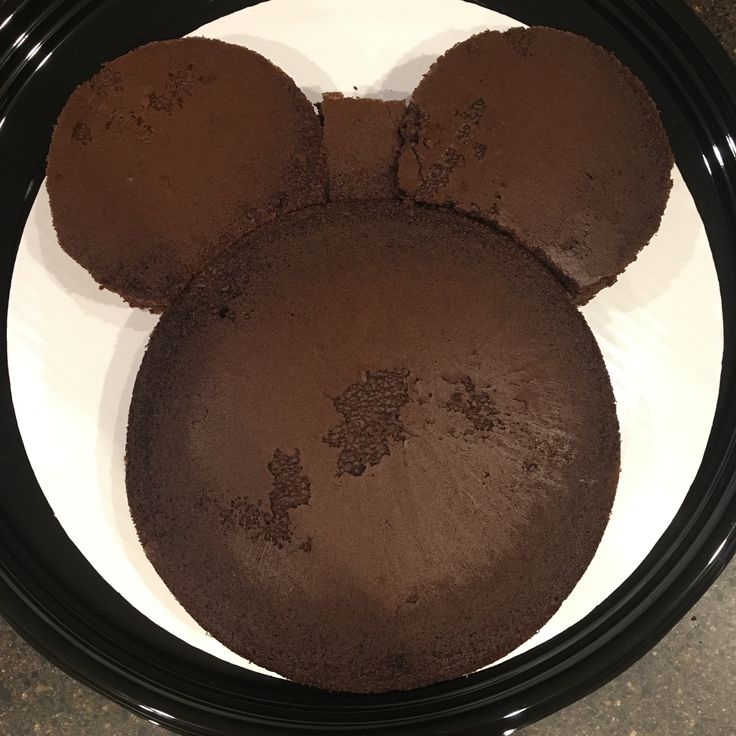 two mickey mouse cookies sitting on top of a white plate with chocolate frosting in the shape of ears