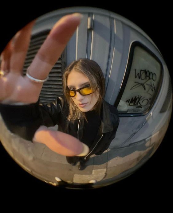 a woman wearing sunglasses and holding her hand up in front of the camera with both hands