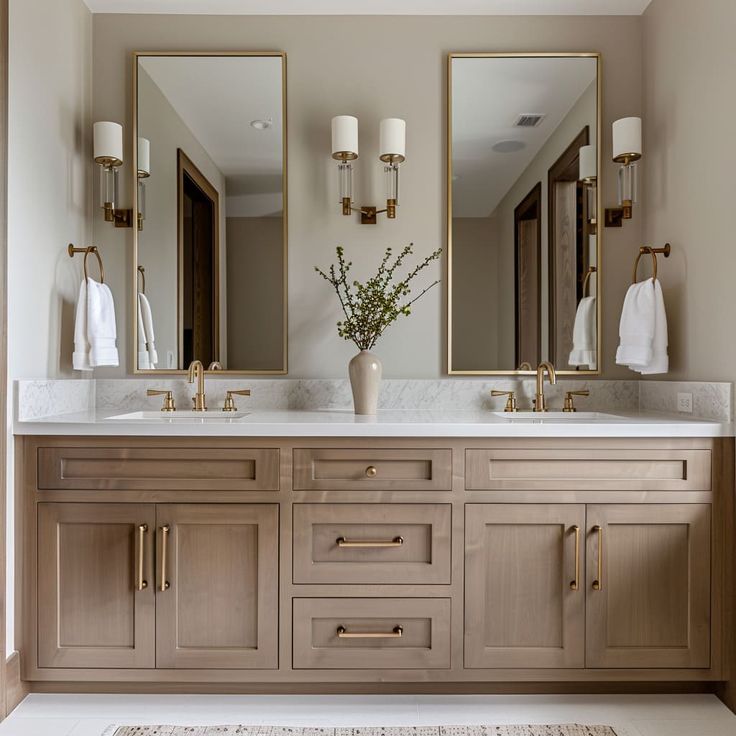 a bathroom with two sinks, mirrors and lights on the wall above them is shown