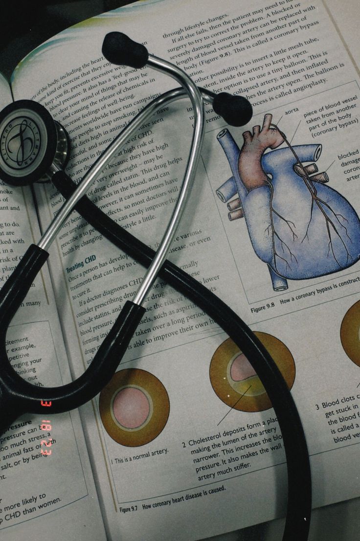 a stethoscope laying on top of an open book with medical illustrations in it