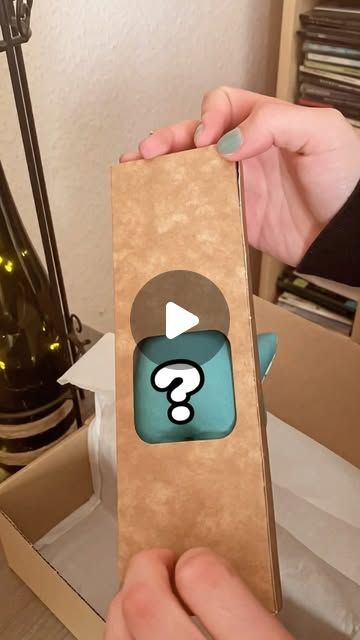 a person holding an open cardboard box with a question mark on the front and side