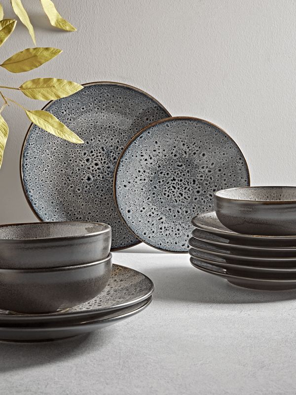 a table topped with plates and cups next to a plant