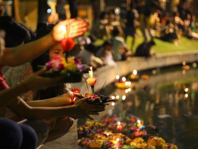 many people are lighting candles on the water