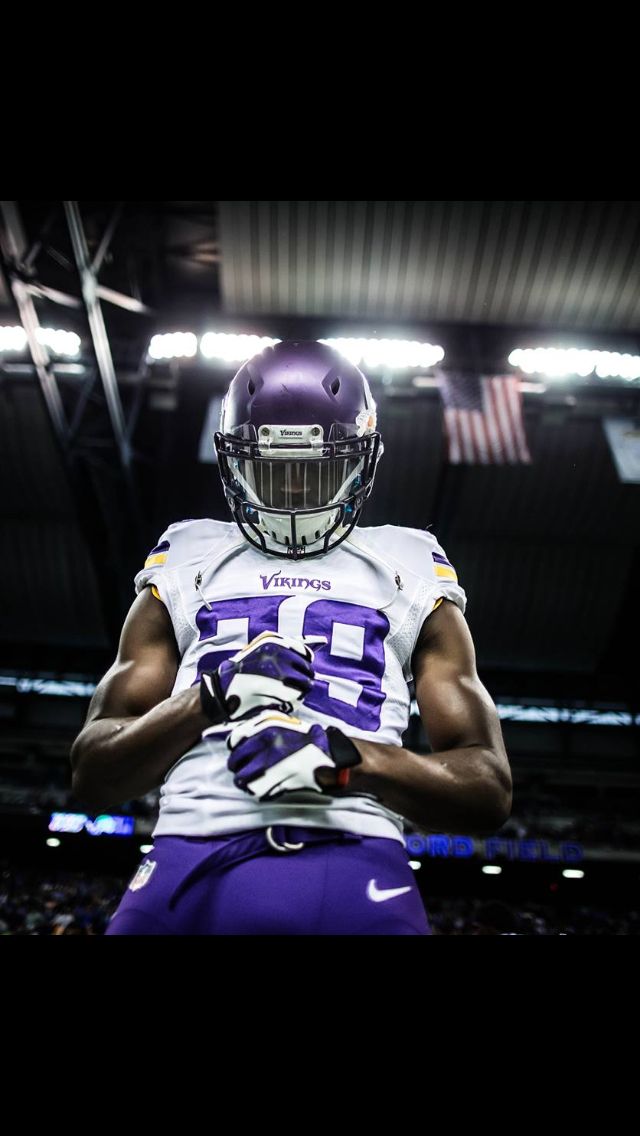 a football player in purple and white uniform with his hands on his hips looking down