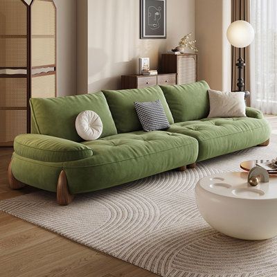 a living room with green couches and white rugs on the floor in front of large windows