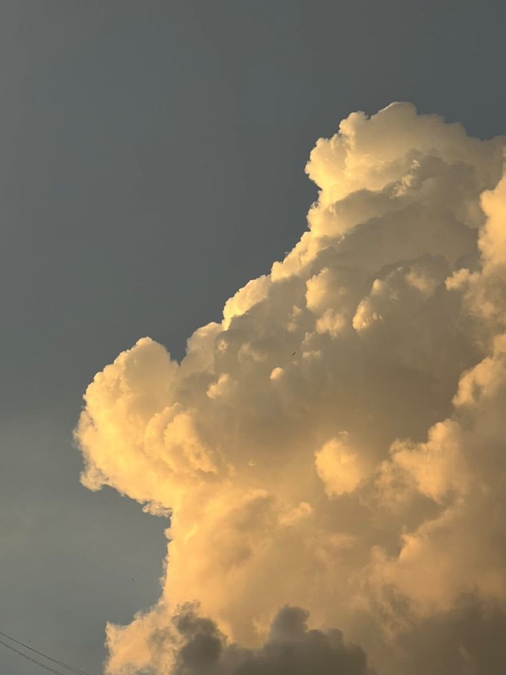 an airplane is flying high in the sky with clouds behind it and power lines below