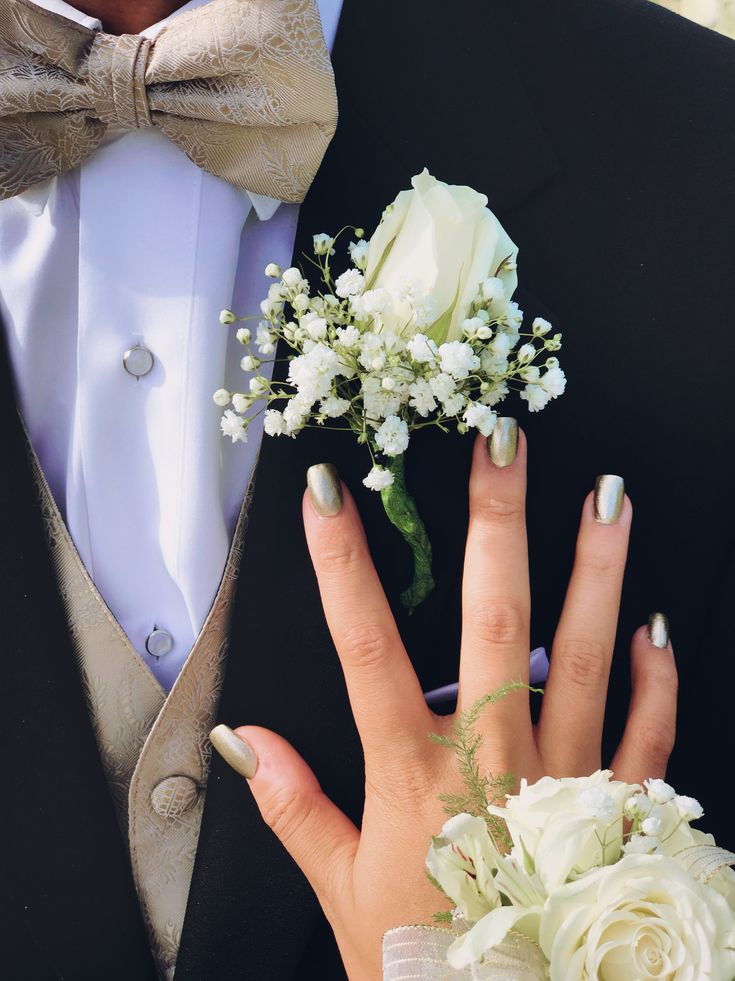 a person in a tuxedo with white flowers and a boutonniere