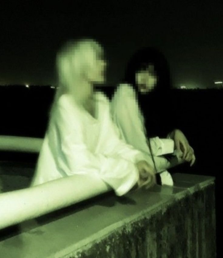 two people sitting on a ledge at night