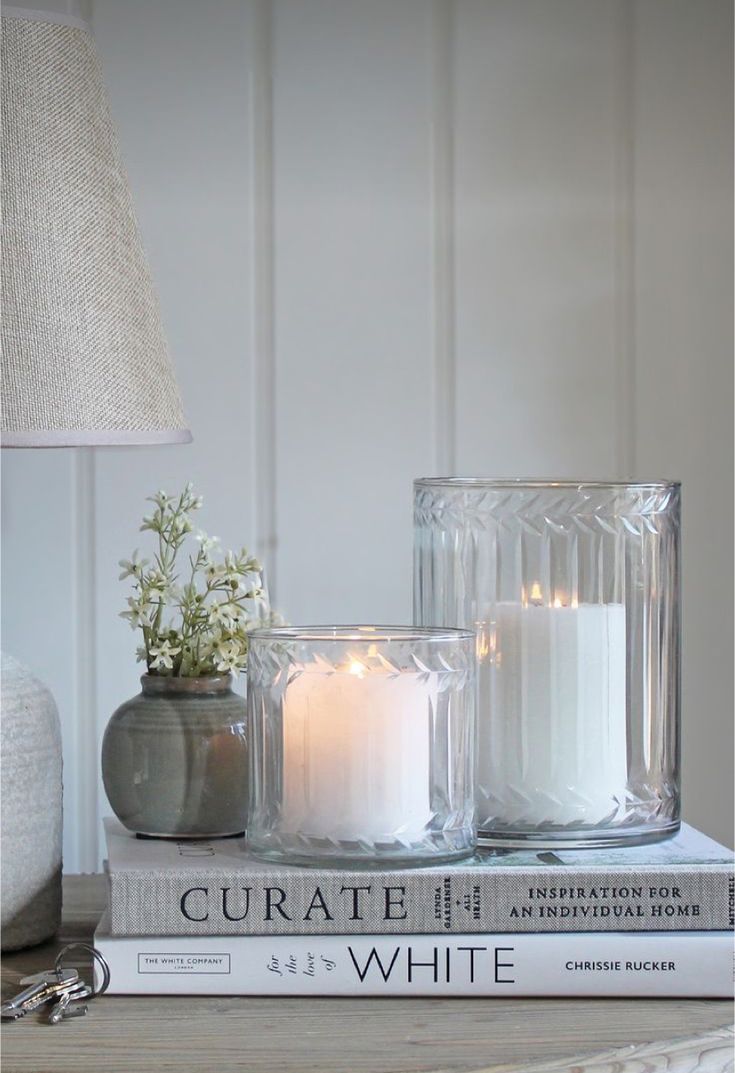 two white candles sitting on top of a stack of books