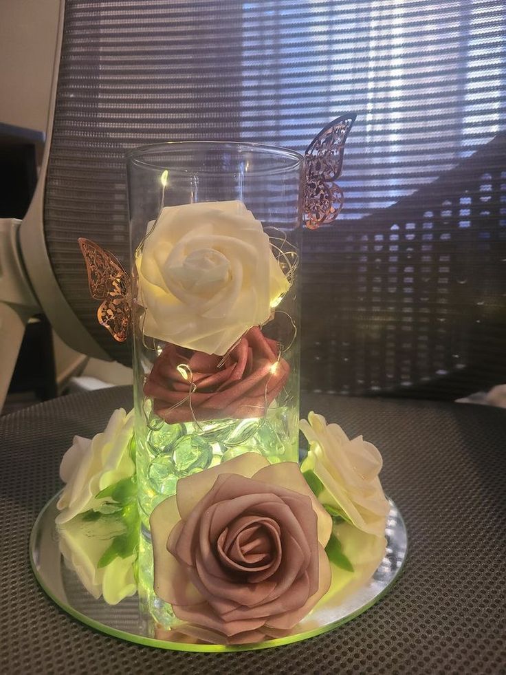 there is a glass vase with flowers in it and a butterfly sitting on top of it