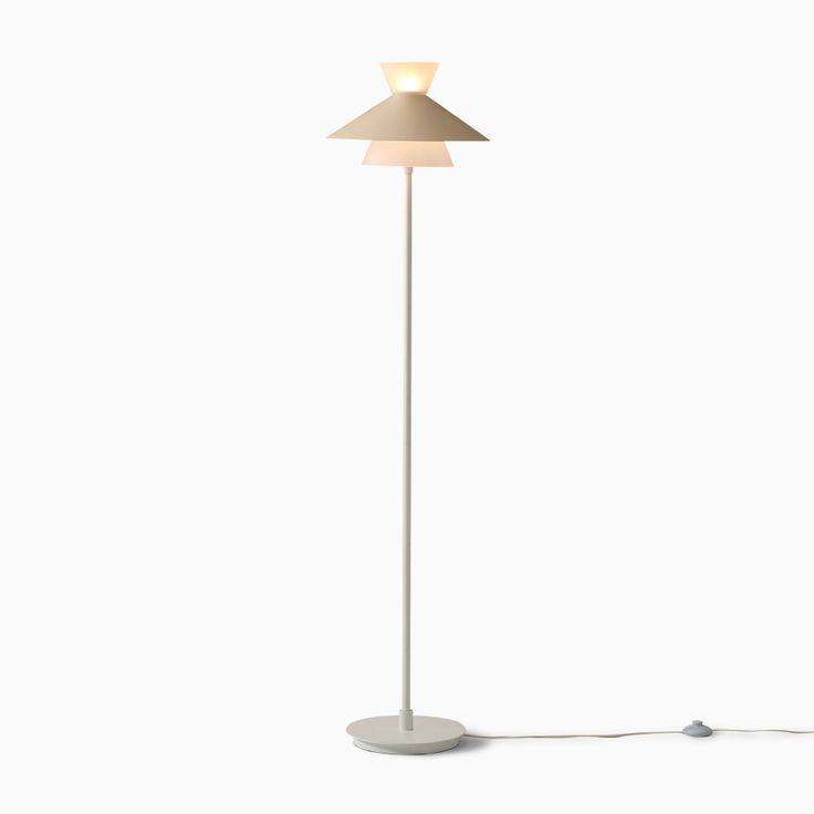 a floor lamp with a white base and a beige shade on the top, against a white background