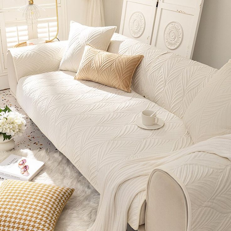 a white bed sitting next to a window covered in pillows and blankets on top of a rug