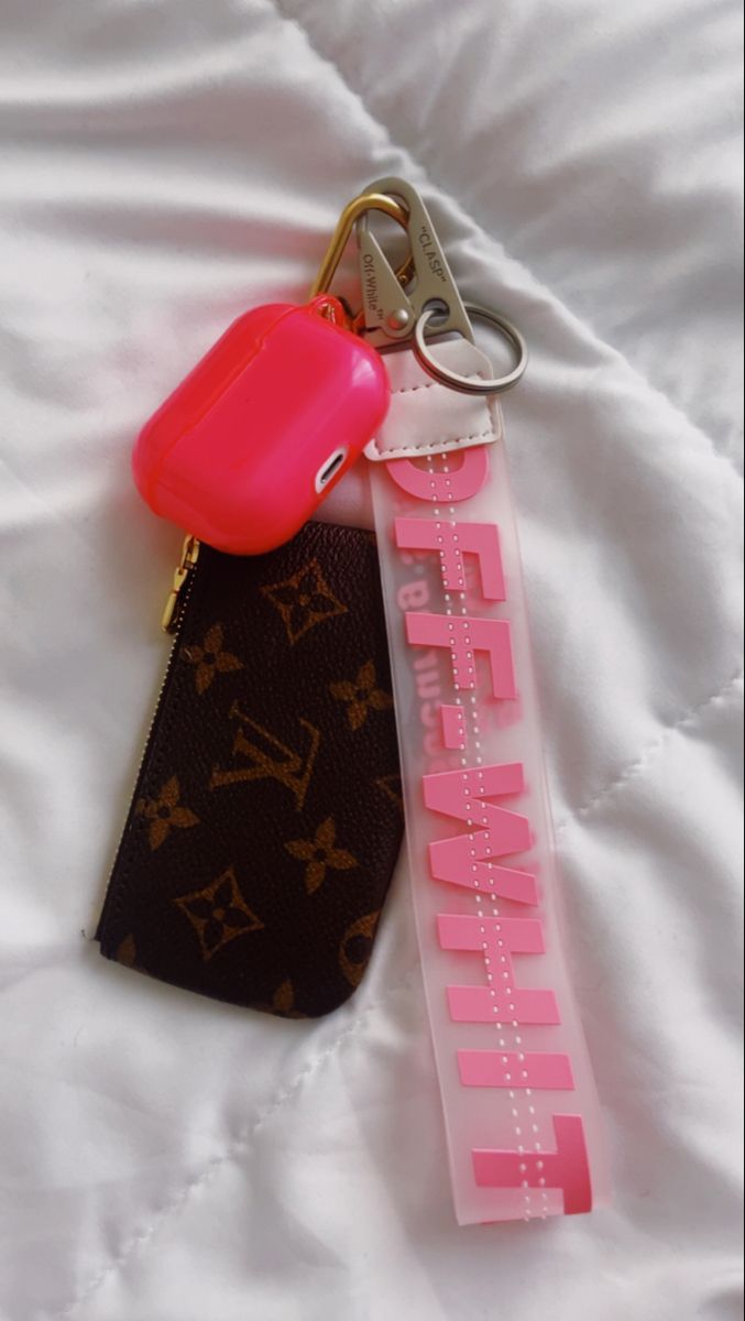 a keychain with a pink plastic object attached to it's side on top of a bed