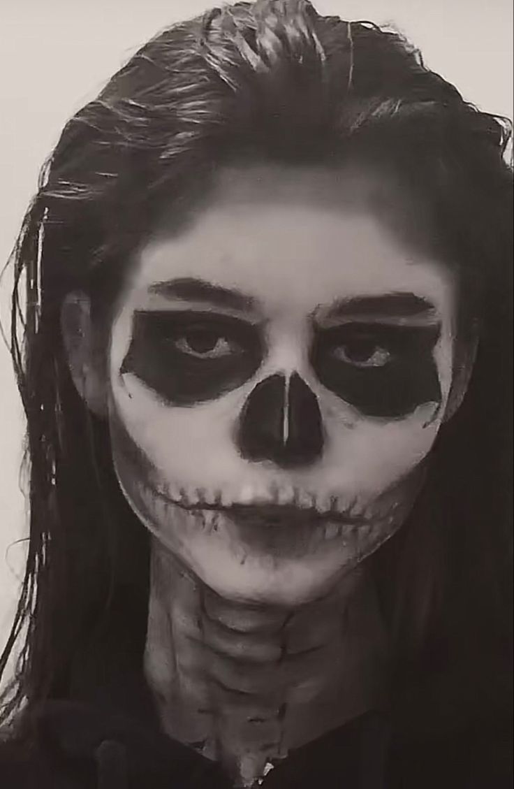 a woman with black makeup and skeleton make - up on her face is looking at the camera