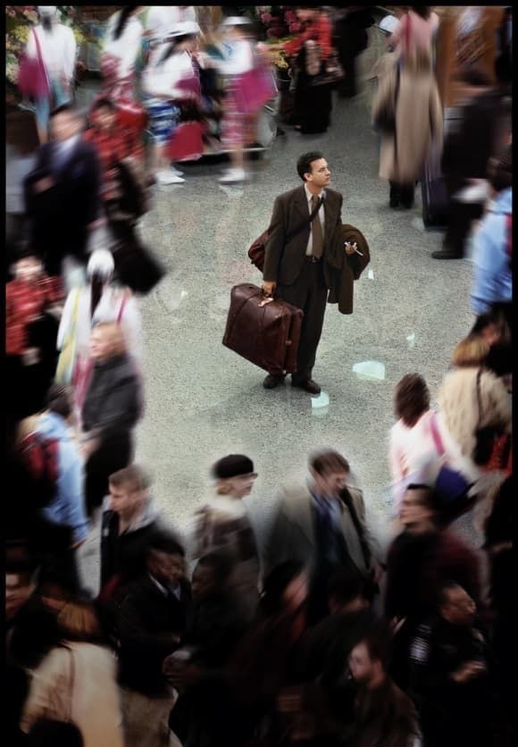 a man in a suit and tie walking through a crowd with his suitcase on the street