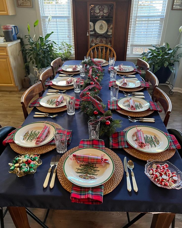 the table is set for christmas dinner with plaid napkins and place settings on it