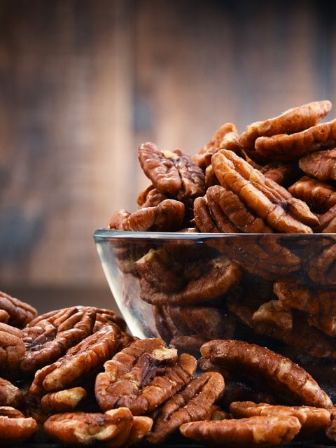 a bowl full of pecans sitting on top of a table next to a plant