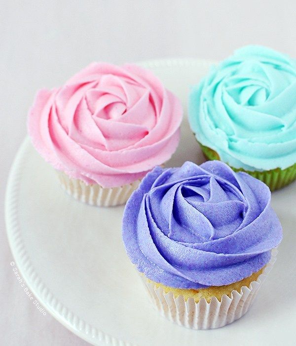 three cupcakes on a plate with frosting in the middle and one pink, one blue