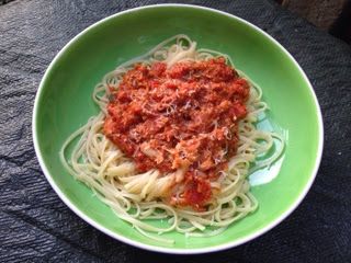 a green bowl filled with spaghetti and sauce