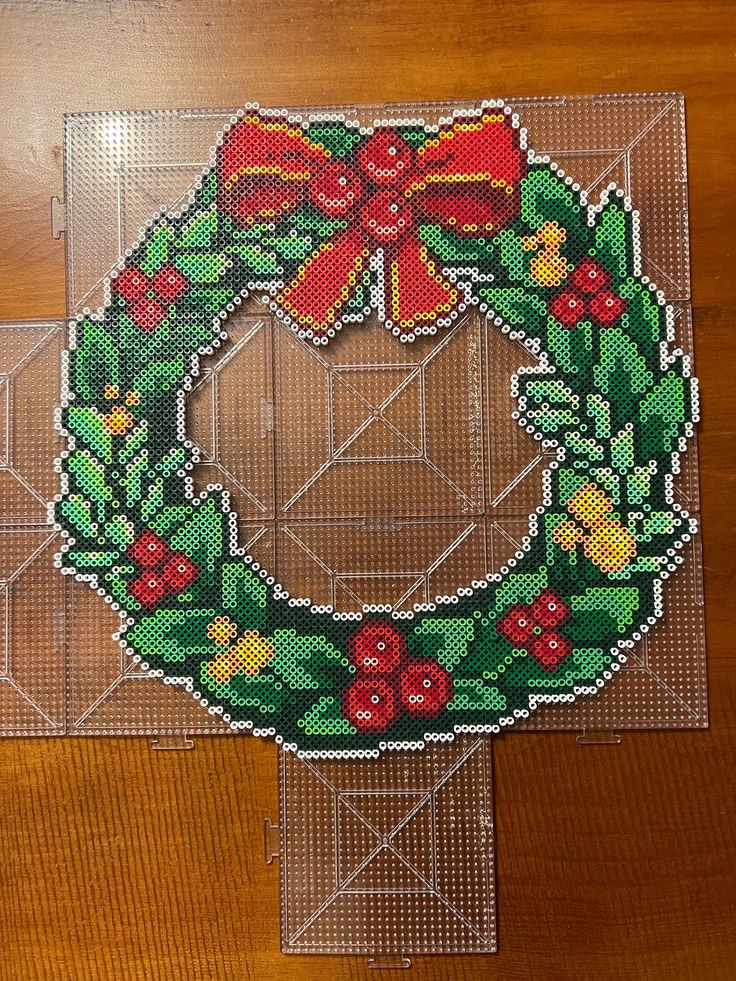 a cross stitch christmas ornament with a bow on it's front and side