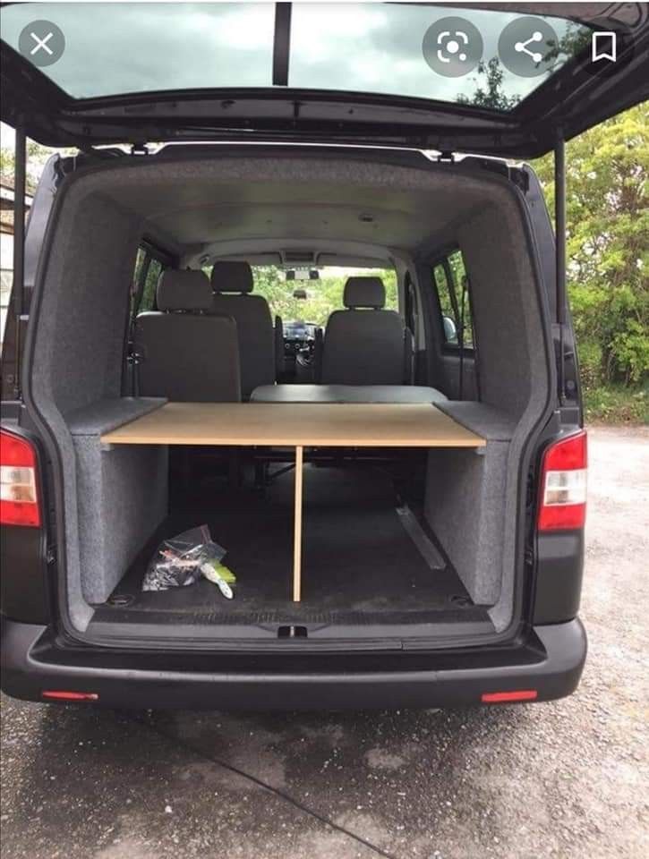 the back end of a van with an open trunk and table in it's cargo area