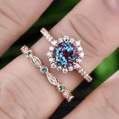 a woman's hand holding two rings with an oval shaped blue and white diamond