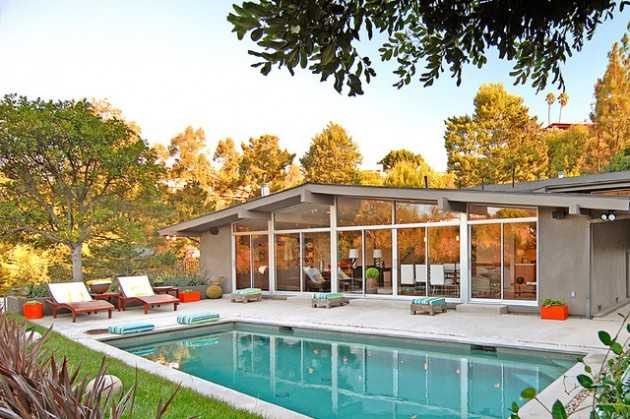 a house with a swimming pool in the yard and lawn chairs on the grass next to it