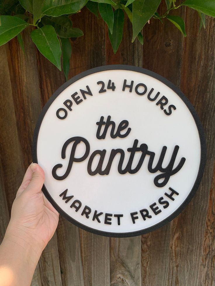 a person holding up a sign that says open 24 hours the pantry and market fresh