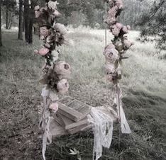 an old book is sitting on the ground next to some flowers and ribbon tied around it