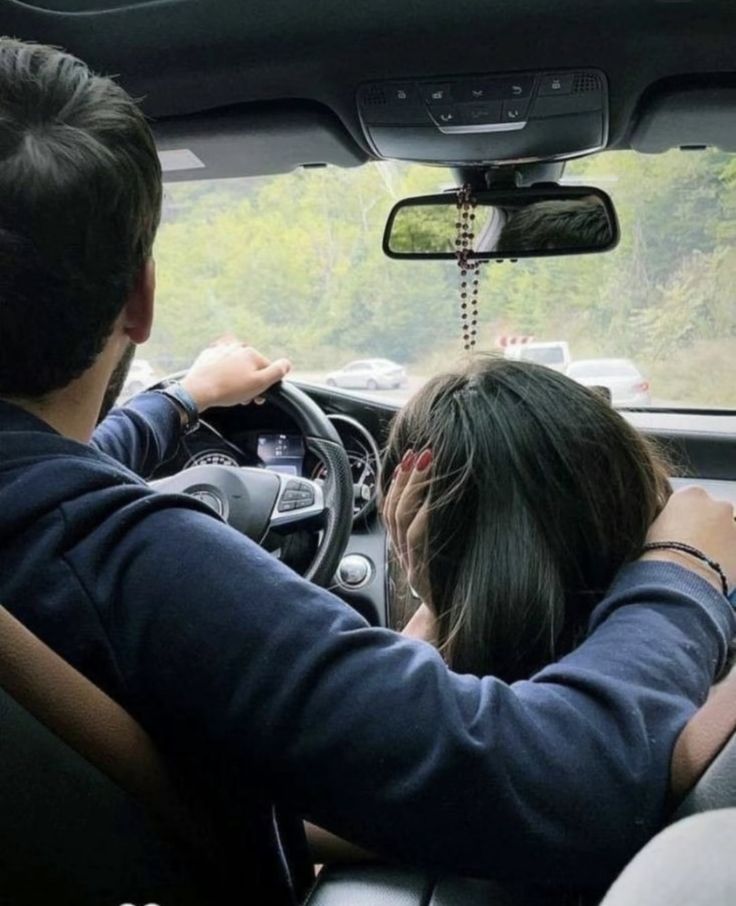 two people sitting in the driver's seat of a car with their hands on the steering wheel