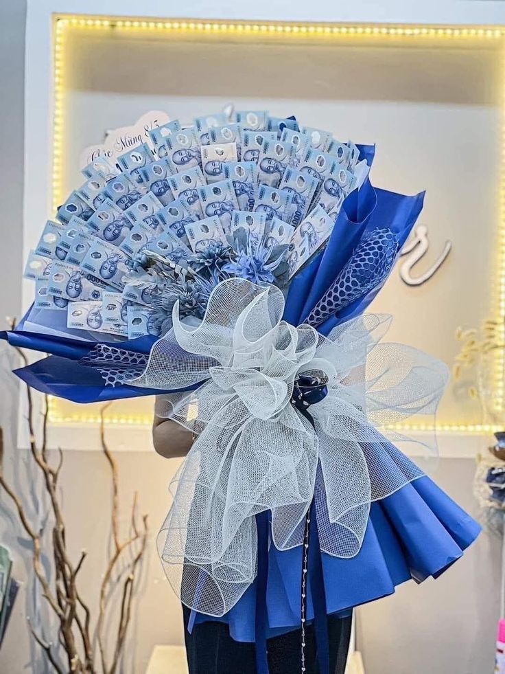 a person holding a blue and white fan with money in it's centerpiece