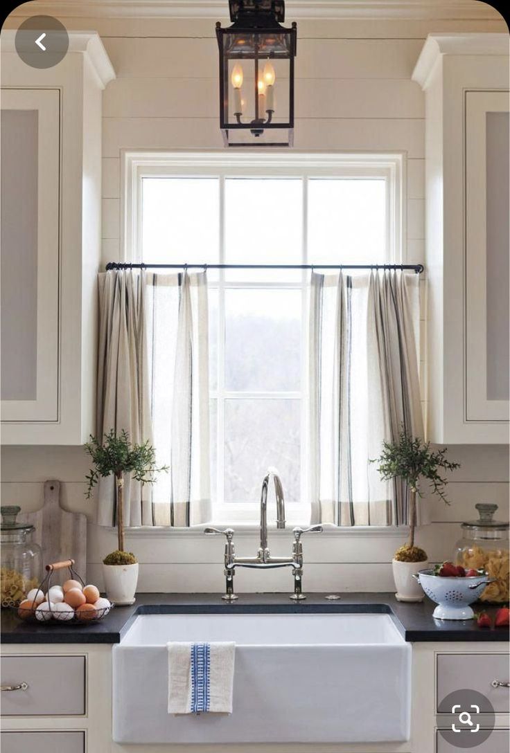 a white kitchen sink sitting under a window