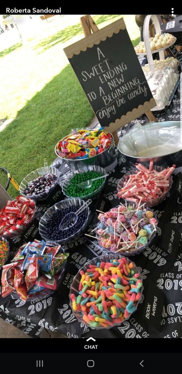 a table full of candy and candies at an outdoor event with a sign in the background