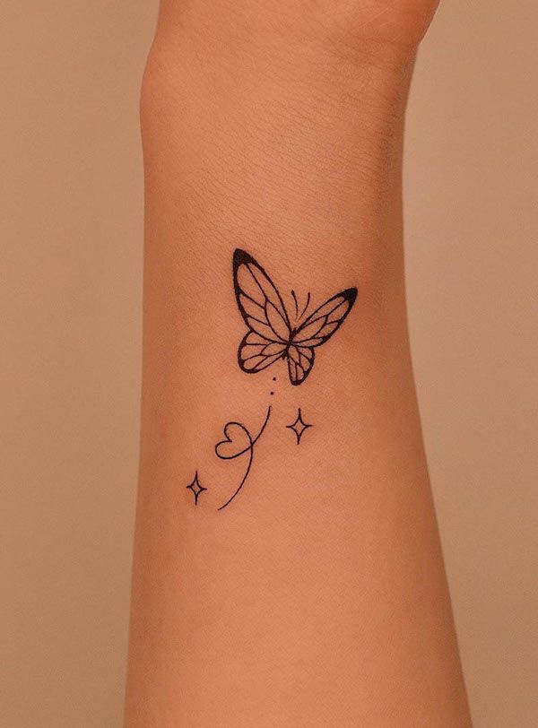 a small butterfly tattoo on the wrist with hearts and stars around it's wings