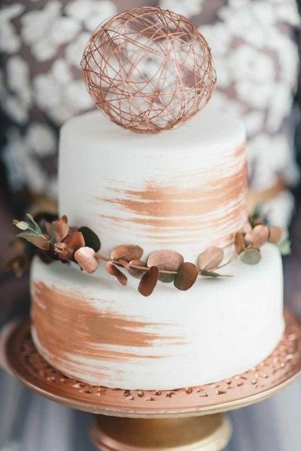 a white and gold wedding cake with an ornament on top