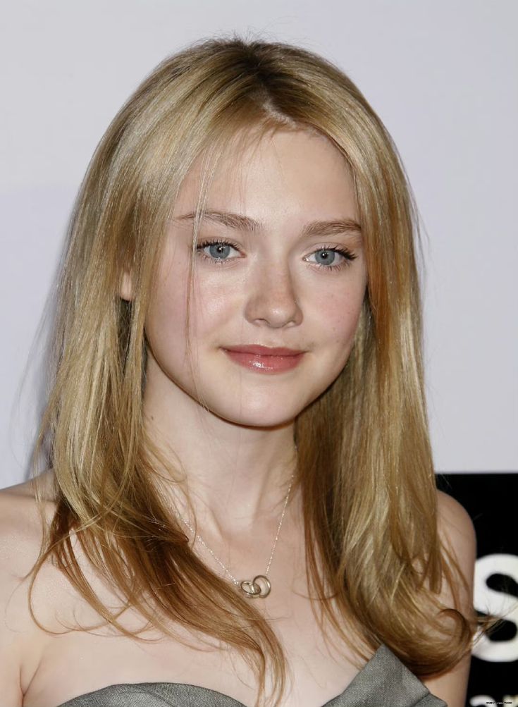 a woman with blonde hair and blue eyes wearing a gray dress smiling at the camera