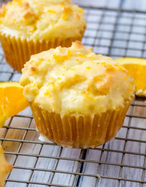 two orange muffins on a cooling rack with one cut in half and the other partially eaten