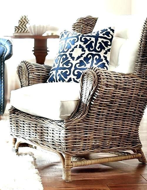 a wicker chair with blue and white pillows in a living room next to a couch