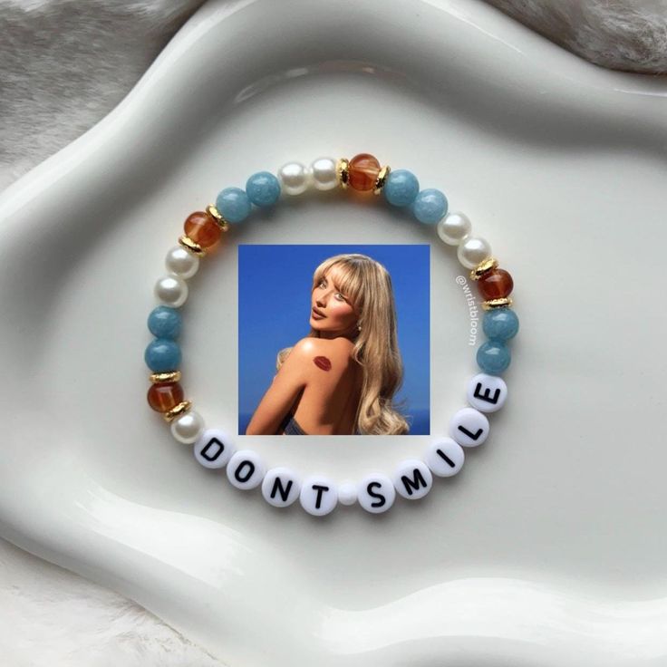 a white plate topped with a beaded bracelet and a photo of a blonde woman