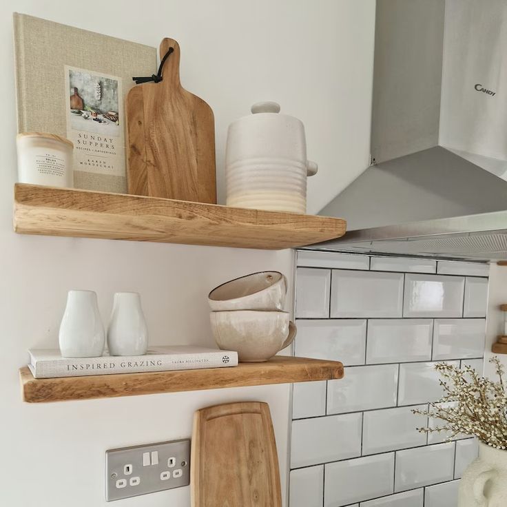 some wooden shelves in a kitchen with white tiles and wood utensils on them