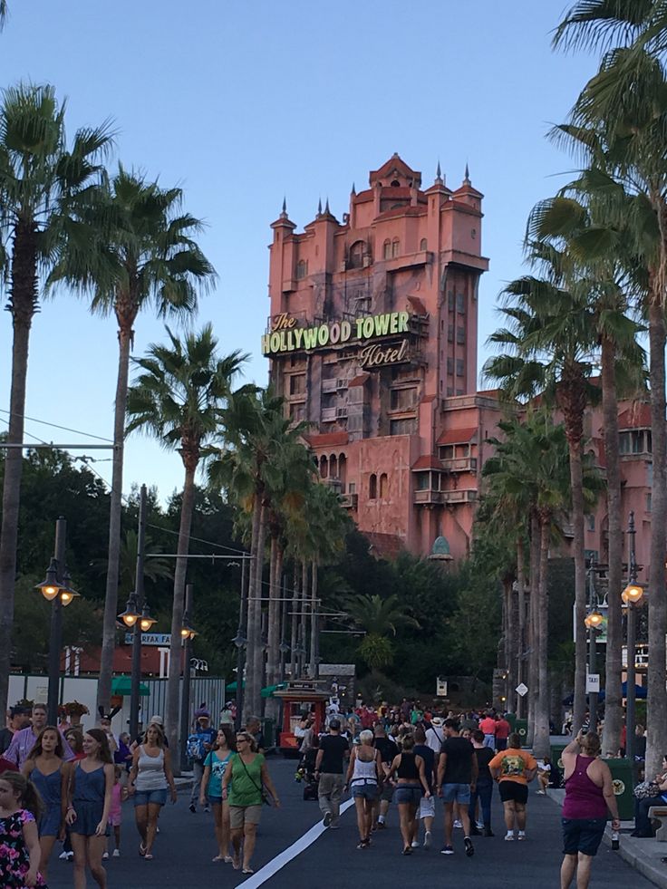 the hollywood tower hotel is surrounded by palm trees and people walking down the street in front