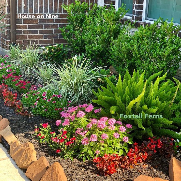 a garden with flowers and plants next to a brick building