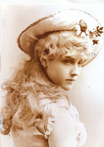 an old fashion photo of a woman with long hair and a hat on her head